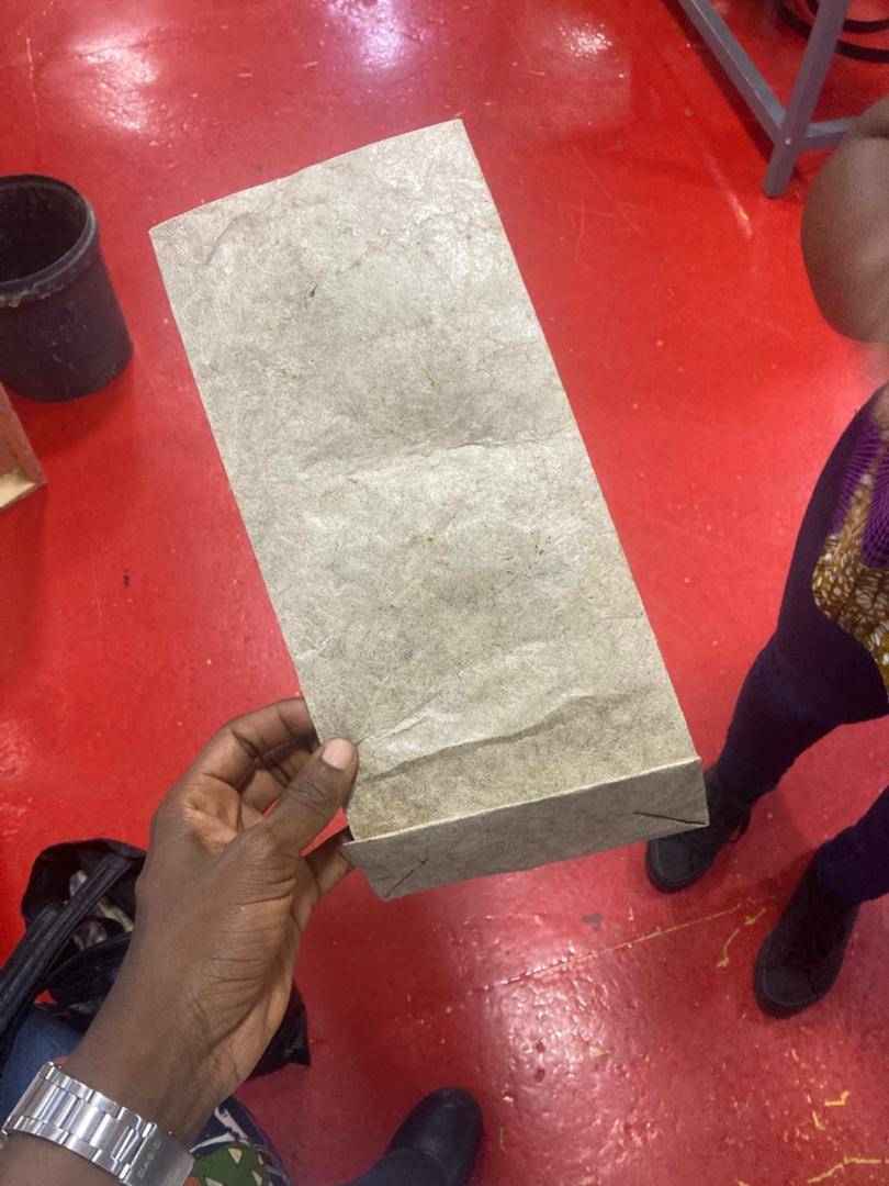 Folded NaturePacks banana-stem paper sample held above the workshop floor